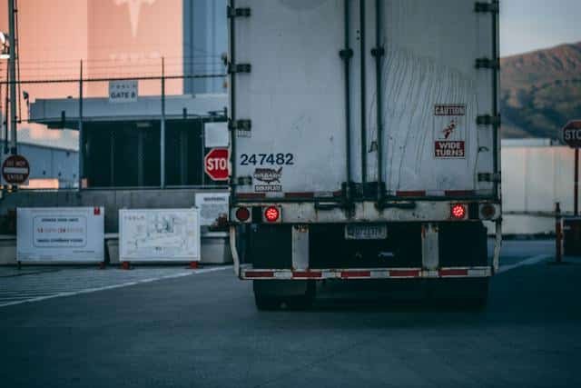 Poids lourd blanc logistique e-commerce à l'arrêt vu de derrière