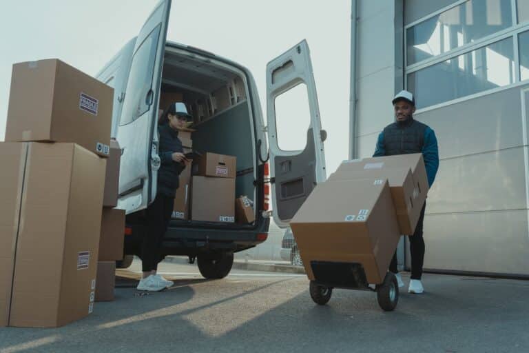 deux personnes en train de décharger des colis de logistique e-commerce d'un véhicule utilitaire