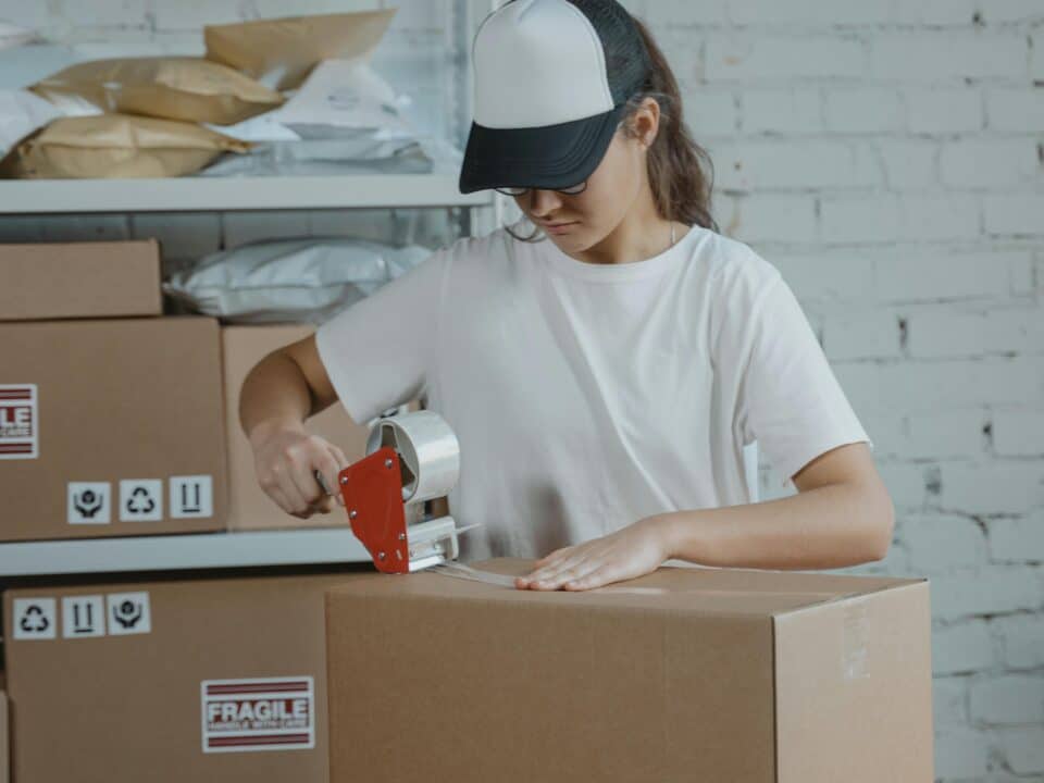 une fille prépare un carton avec une scotcheuse