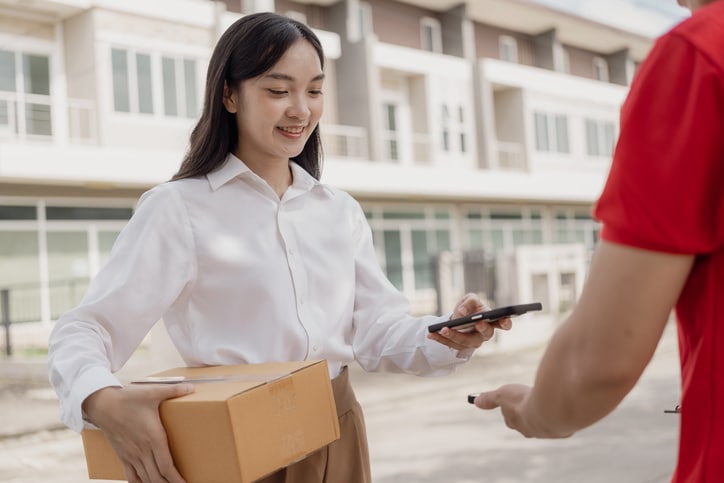 Une femme reçoit son colis et Scan le téléphone du livreur