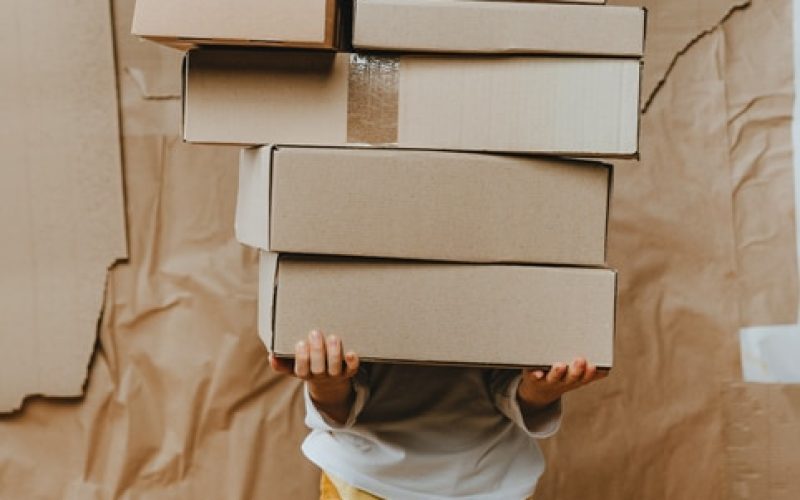 un enfant avec un pile de colis à la main